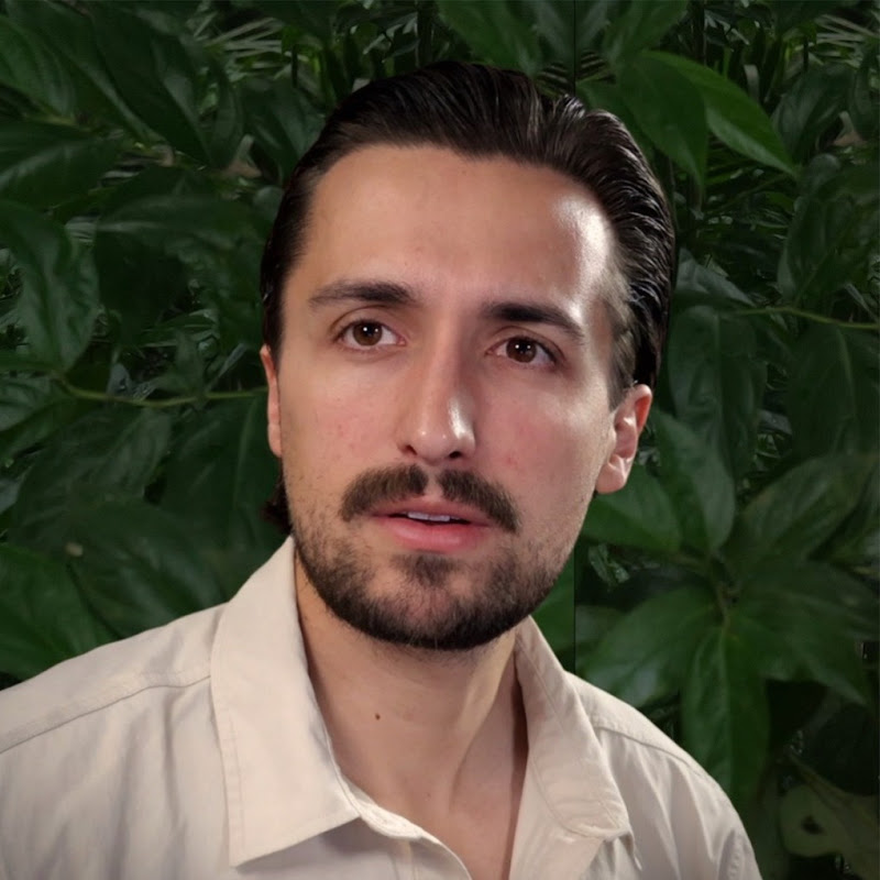 Luke Caverns in a khaki field shirt against a wall of jungle leaves